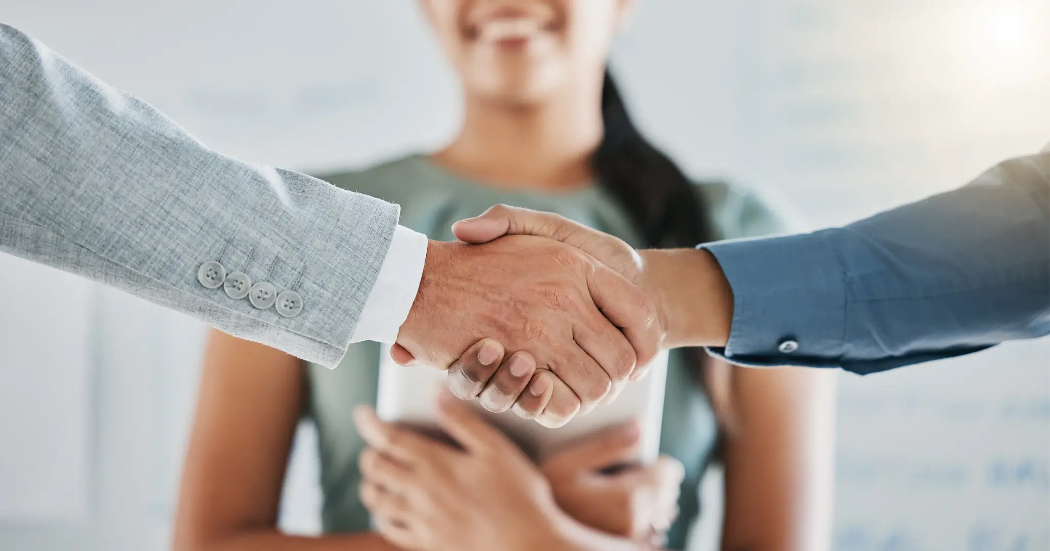 Two businessmen shaking hands in front of a new hire